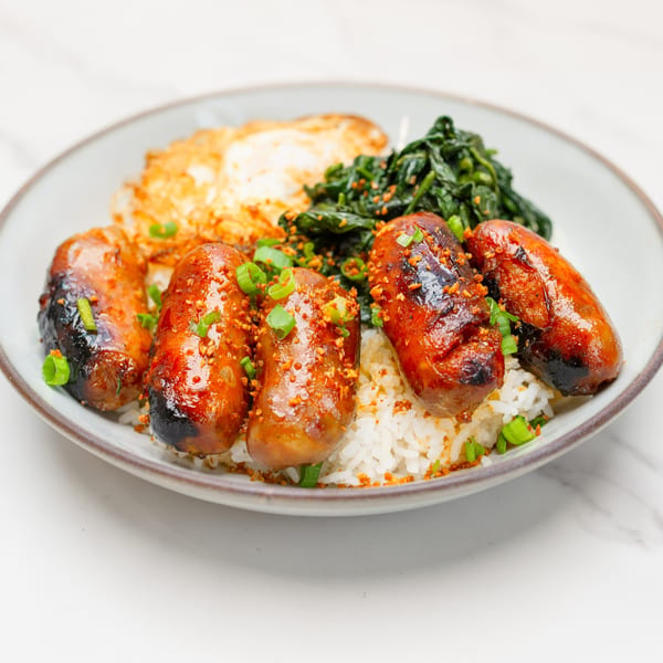 Take Ur Seat's brunch plate with five grilled sausages, rice, fried egg, and greens.
