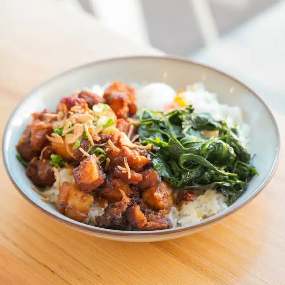 A bowl of Take Ur Seat's brunch with rice, braised pork, greens, and a fried egg.